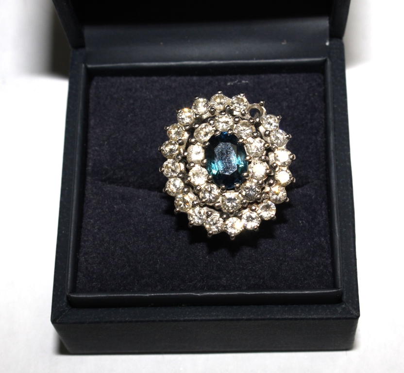A large cluster ring with two rows of diamonds and a central sapphire set in 18 carat white gold (