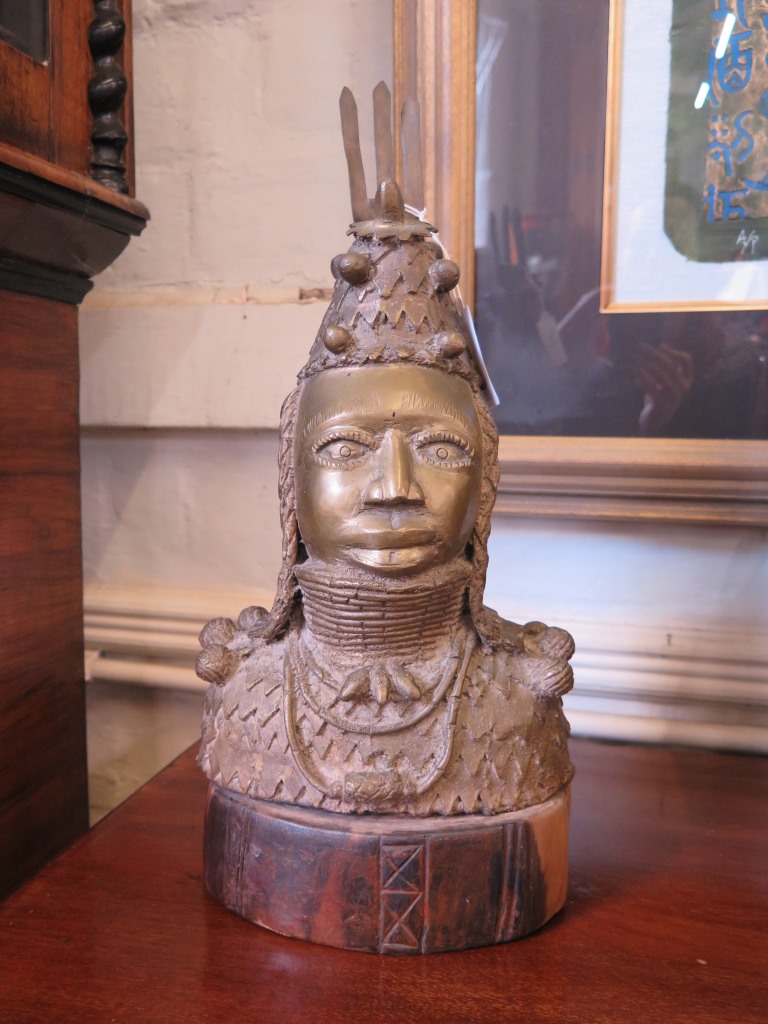 A Benin bronze bust of a figure in ceremonial dress, on a hardwood base 39cm high