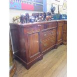 An Edwardian inverted breakfront sideboard, with frieze drawer over two graduated drawers flanked by