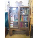 An Edwardian oak bookcase, the raised scroll top above a pair of glazed doors on large bracket