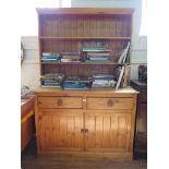 A pine dresser and associated rack, with two short drawers above a pair of panelled doors on a