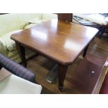 An Edwardian mahogany extending dining table, the rectangular top with canted corners on square