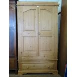 A pine wardrobe, the twin panelled doors over a long drawer on bracket feet, 110 cm wide, 194 cm
