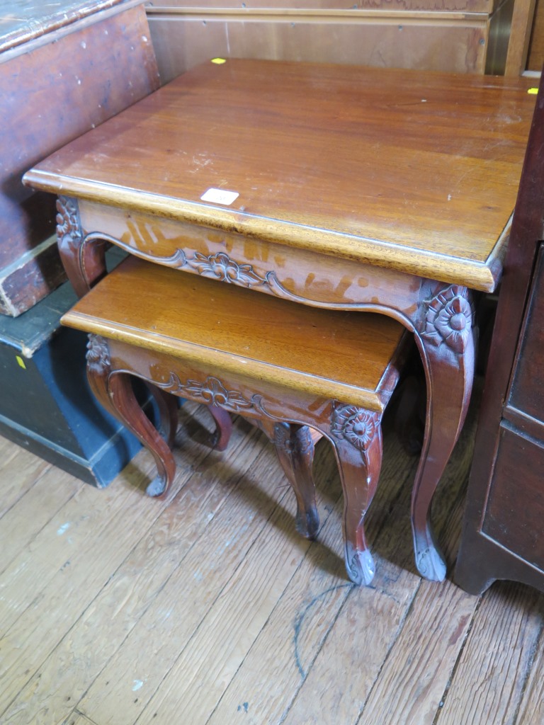 A nest of three French style teak tables with floral carving and cabriole legs, largest 60cm wide,