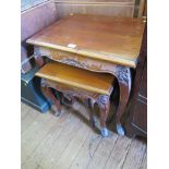 A nest of three French style teak tables with floral carving and cabriole legs, largest 60cm wide,