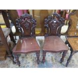 A pair of Victorian mahogany hall chairs, the pierced scroll carved backs with floral motif over