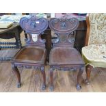 A pair of Regency mahogany hall chairs, the C-scroll carved backs with squirrel crest and painted