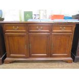 A mahogany side cabinet with three short drawers over three panelled doors on bracket feet, 142cm