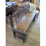 A late Victorian carved oak hall bench, the mask and dolphin crest on a lunette carved frieze and