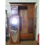 An Edwardian inlaid mahogany wardrobe, with oval mirrored door and long drawer 131cm wide, 52cm