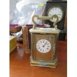 An Edwardian brass carriage clock, with bowed sides and applied foliate sprays, the circular