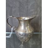 A small silver cream jug decorated in relief, Birmingham 1907