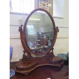 A Victorian mahogany toilet mirror, the oval plate on scroll supports over a shaped base with two