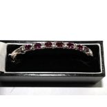 A hinged silver bangle, set with seven garnets in an Andre Noir fitted case