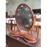 A Victorian mahogany toilet mirror, the oval plate on scroll supports over a shaped base with two