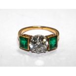 A hallmarked 18 carat gold tested emerald and diamond three stone dress ring, the old cut claw set