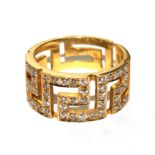 A gold colour metal ring set with diamonds in the form of a Greek key pattern