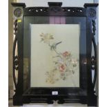 An Edwardian ebonised fire screen containing a silk embroidered panel depicting a bird on a rose