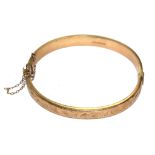 A 9 carat gold bangle with decoration to one half in relief