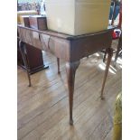 A George II mahogany side table, the dished top with indented corners over a frieze drawer on