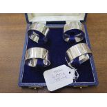 A collection of four silver napkin rings, cased