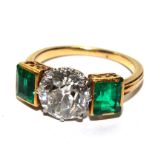 A hallmarked 18 carat gold tested emerald and diamond three stone dress ring, the old cut claw set