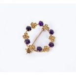 A YELLOW METAL AMETHYST COLOURED STONE AND SEED PEARL SET CIRCULAR BROOCH 2.2cm across