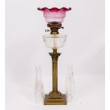 A 20TH CENTURY CORINTHIAN COLUMN BRASS OIL LAMP with cut glass reservoir, unassociated cranberry