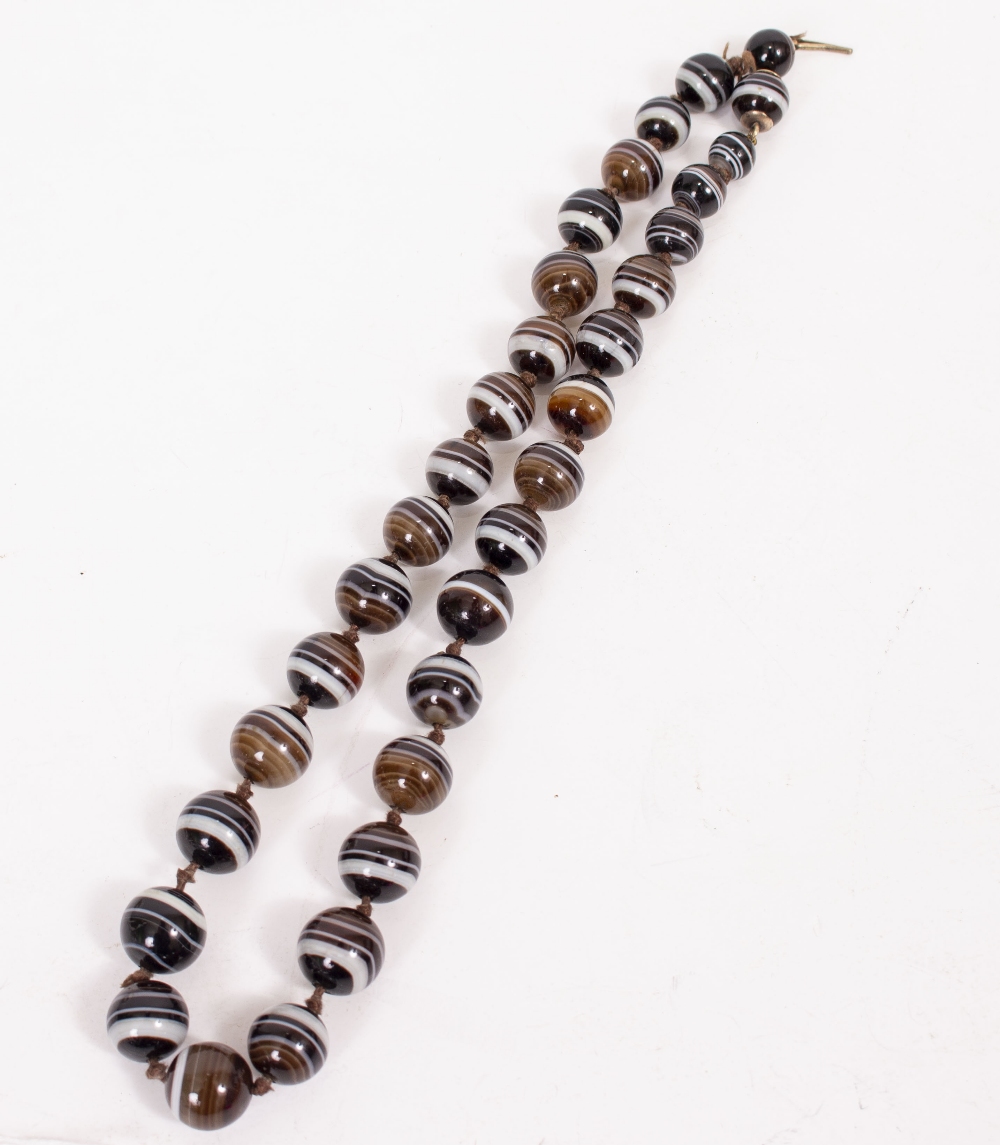 A BEADED BANDED AGATE NECKLACE the largest bead approximately 1.3cm diameter, the necklace 52.5cm