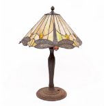 A CAST METAL BASED TABLE LAMP with a leaded glass Tiffany style lamp shade, decorated with