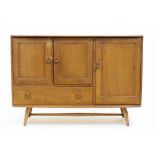 AN ERCOL LIGHT ELM SIDEBOARD with three cupboards, a single drawer and turned supports, 114cm wide x