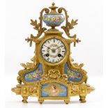 A CONTINENTAL GILT SPELTER MANTLE CLOCK the shaped case with vase finial and inset with porcelain