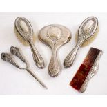 A SILVER BACKED DRESSING TABLE SET consisting of a hand mirror, a pair of brushes and a comb, each