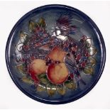 A CONTEMPORARY MOORCROFT POTTERY CHARGER decorated with birds amongst fruit on a blue ground, 35cm