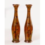 A PAIR OF SECESSIONIST STYLE AMBER GLASS VASES of slender form with applied copper stylised