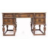 A 17TH CENTURY STYLE OAK DESK with leather inset top, five drawers, and cup and cover supports 140cm