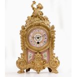 A GILT SPELTER PORCELAIN MOUNTED TIMEPIECE or clock, the case surmounted by a sculpture of a boy