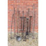 A COLLECTION OF GARDEN TOOLS and implements to include forks, spades, rakes, a hose etc., (a