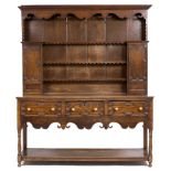 AN 18TH CENTURY STYLE OAK FARMHOUSE DRESSER with a shaped frieze, open shelves with two fitted