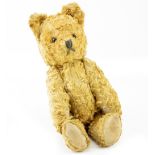 A 20TH CENTURY TEDDY BEAR with glass eyes, unsigned and label, with stitched paws 21cm approximately