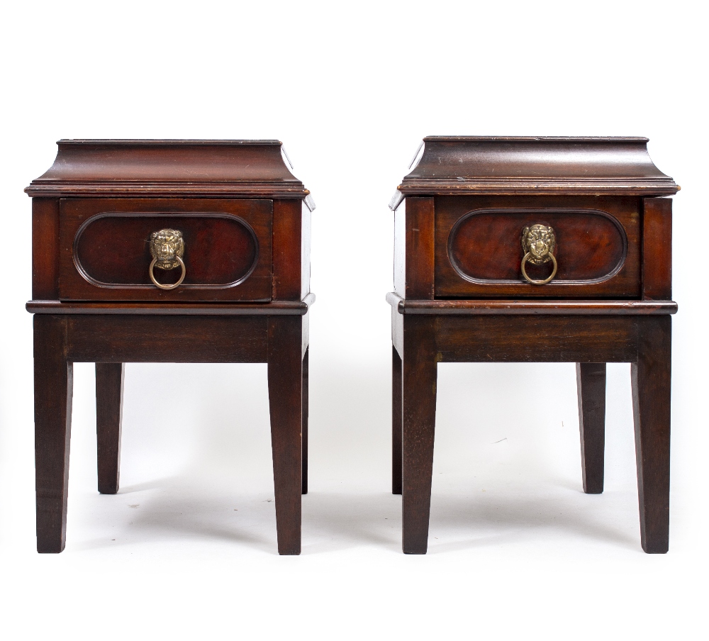 A PAIR OF MAHOGANY BEDSIDE CHESTS with sarcophagus tops, brass lion handles, standing on square