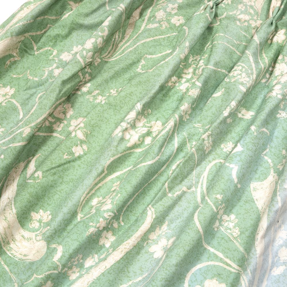 A PAIR OF COTTON PRINTED CURTAINS on a green ground with a white repeating foliate motif, fully