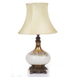 A GILT WHITE GLASS TABLE LAMP of squat ovoid form with a band of flower decoration and cast brass