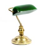 A BRASS DESK LAMP with green glass shade and spreading circular base, 25cm wide x 38cm high