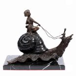 A BRONZE STATUE depicting a cherub riding a snail on a black hardstone base 33cm wide x 27cm high