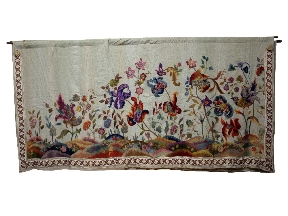 AN EARLY 20TH CENTURY CREWEL WORK EMBROIDERED PANEL worked in coloured threads on linen,