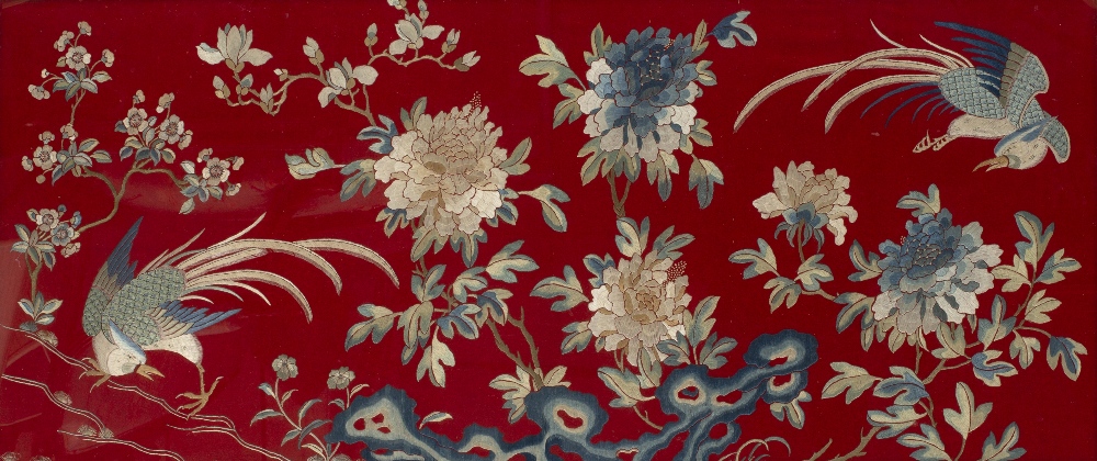A CHINESE EMBROIDERED PANEL of phoenix amongst branches and flowers on a red felt ground, 56cm x