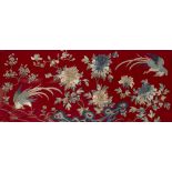 A CHINESE EMBROIDERED PANEL of phoenix amongst branches and flowers on a red felt ground, 56cm x