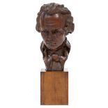 AN OLD BLACK FOREST CARVED SCULPTURAL BUST of Beethoven on a wooden plinth, with a brass label to