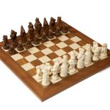 A MODERN CAST COMPOSITE CHESS SET on a walnut and birch inlaid chess board, the chess pieces